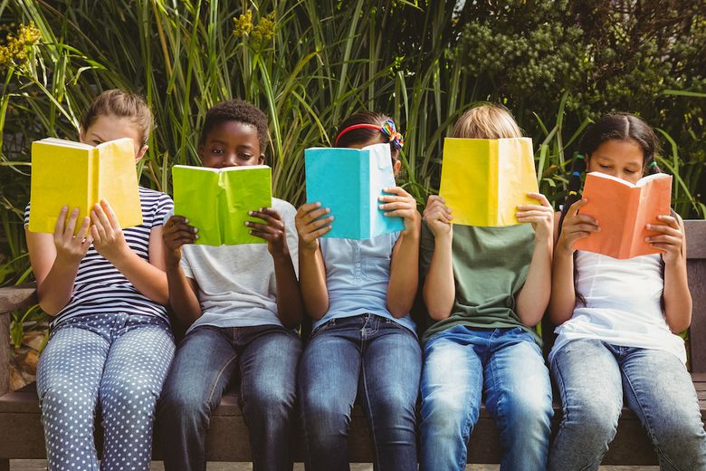 Lesende Kinder sitzen auf einer Mauer. Lesende Kinder sitzen auf einer Mauer.