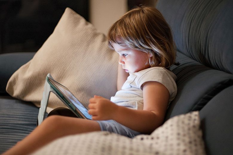 Bildschirmzeit Ein Tablet wirft kaltes Licht auf das Gesicht eine Kindes.
