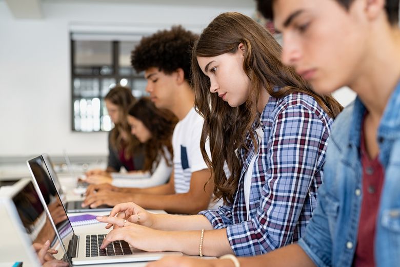 Group of high school students using laptop in classroom Eine Gruppe von jungen Menschen im Unterricht.