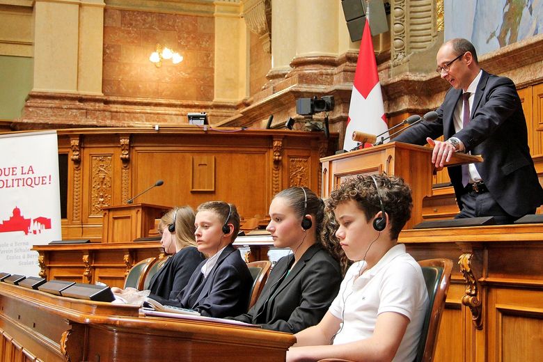Politische Bildung Jugendliche sitzten im Bundeshaus, wo normalerweise gewählte Volksvertreter und Volksvertreterinnen sitzen.
