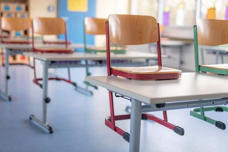 Red chair in a classroom stands on a table Symbolbild: Leere Stühle und Tische in einem Schulzimmer.