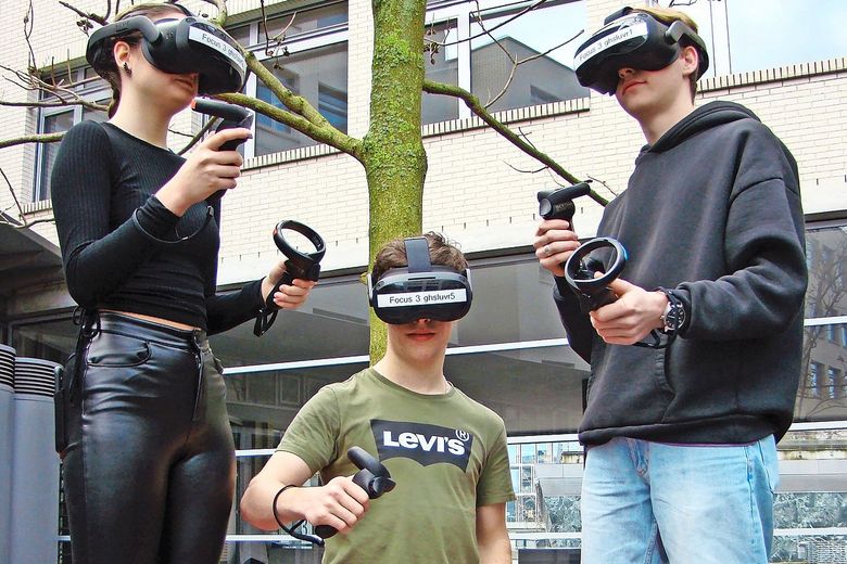 Virtual Reality in der Berufsbildung Drei Lernende tragen VR-Brillen und halten dabei Steuerelemente in ihren Händen.