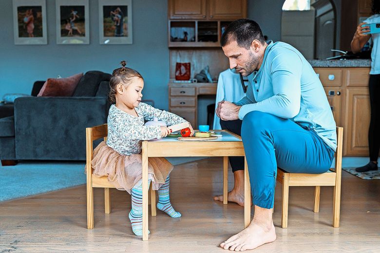 Bildschirmzeit Ein Vater sitzt mit seinem Kind an einem Spieltisch.