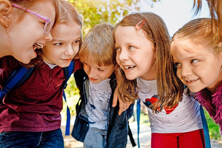 Eine Gruppe fröhlicher Kindern steckt verschwörerisch die Köpfe zusammen.