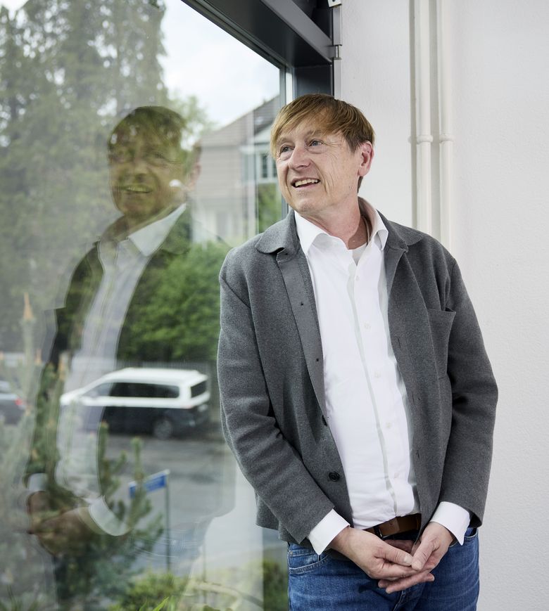 Preisüberwacher Stefan Meierhans lehnt an einem Fenster und schaut nach draussen.