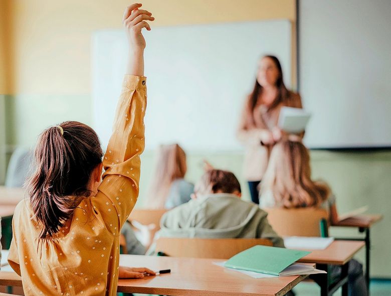 Schulkinder strecken Arme in die Höhe.