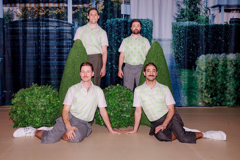 Drei Männer in grauen Hosen und grünweiskarierten Poloshirts stehen auf einer Bühne.