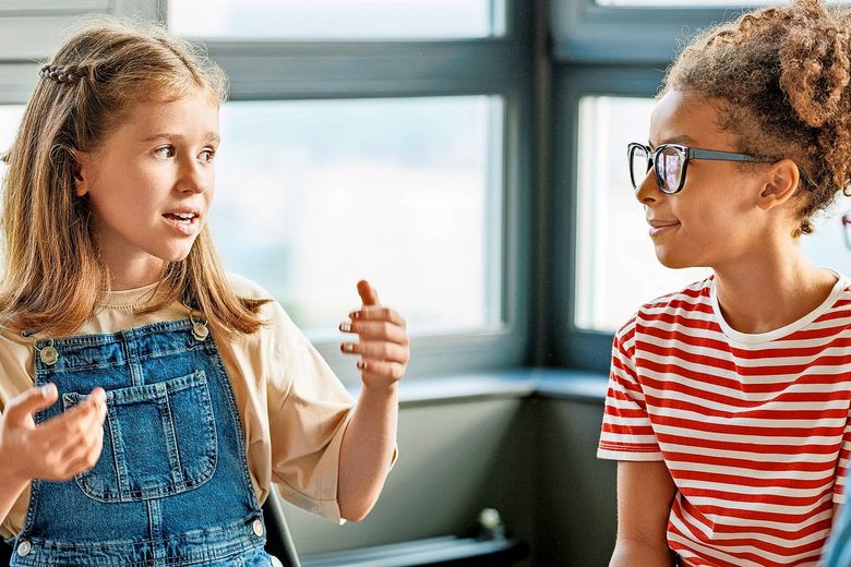 Drei Schulkinder sind in eine Unterhaltung vertieft.